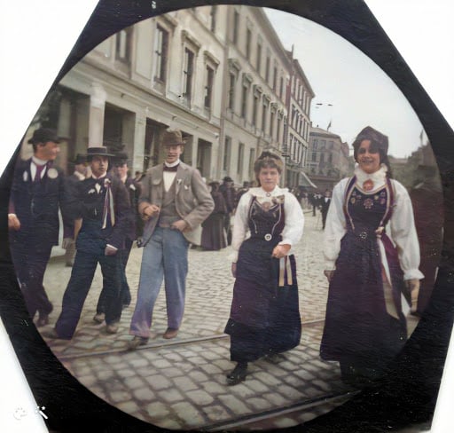 Mennesker på gaden, inklusive to kvinder i traditionelt norsk påklædning. En af dem smiler til kameraet