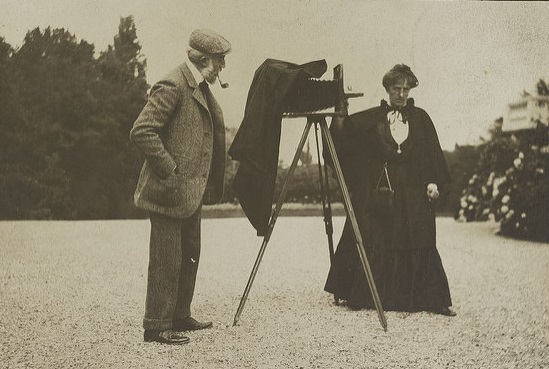 El fotógrafo Gertrude Käsebier, de pie junto a una cámara montada en un trípode.