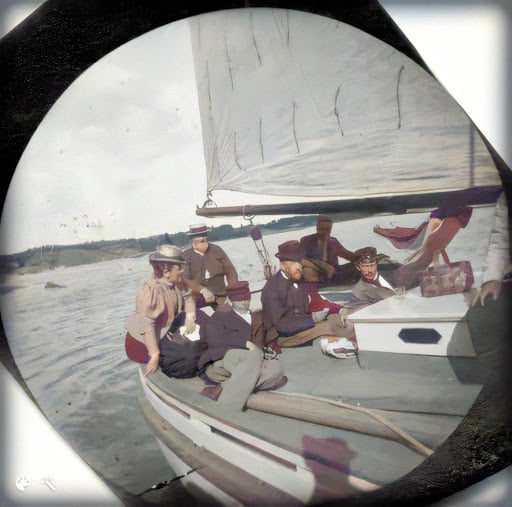 A group of people sit on the stern of a sailboat