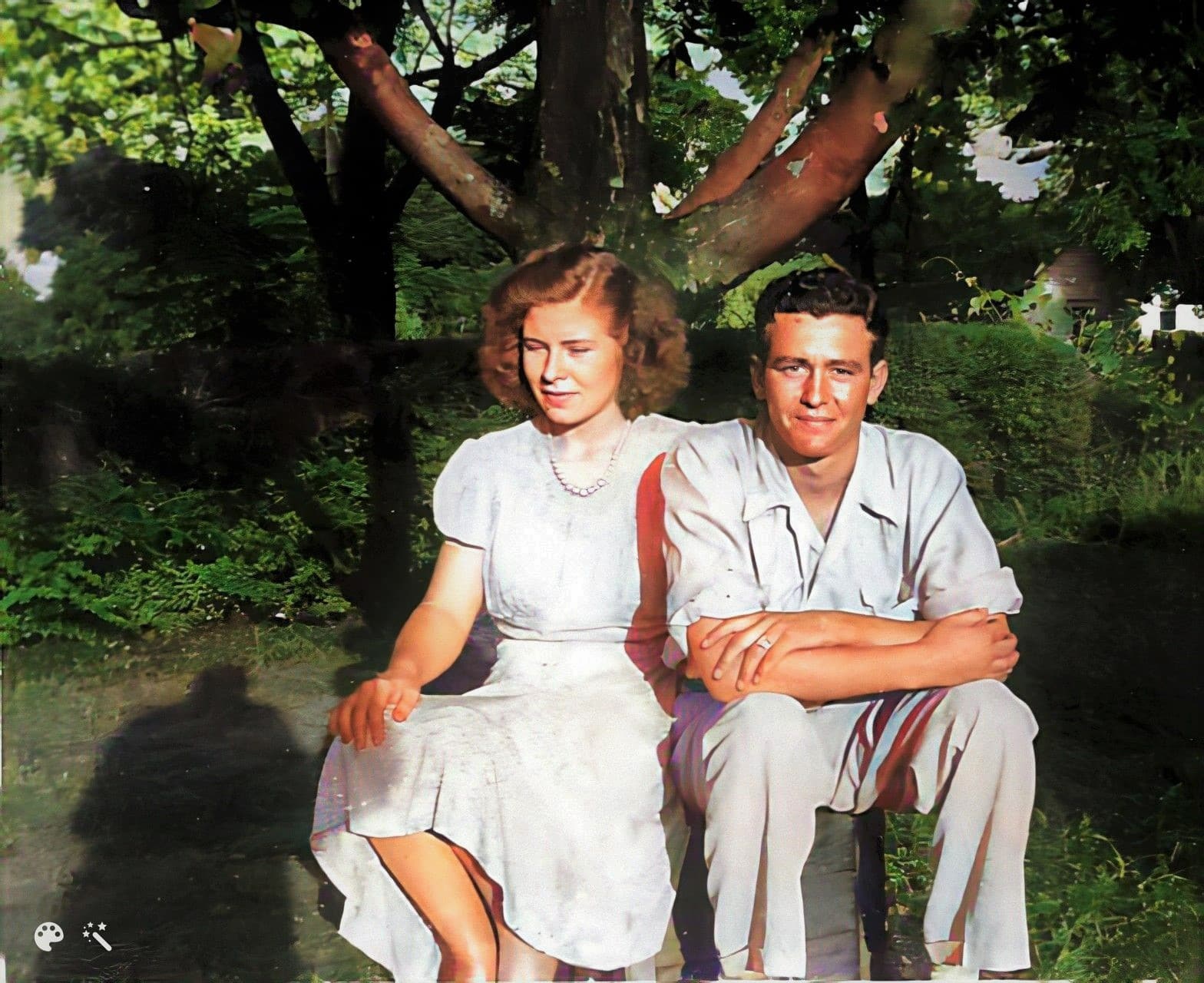 Janis' mor og biologiske far, sidder side om side i hendes bedstefars have før krigen. Foto forbedret og farvelagt af MyHeritage
