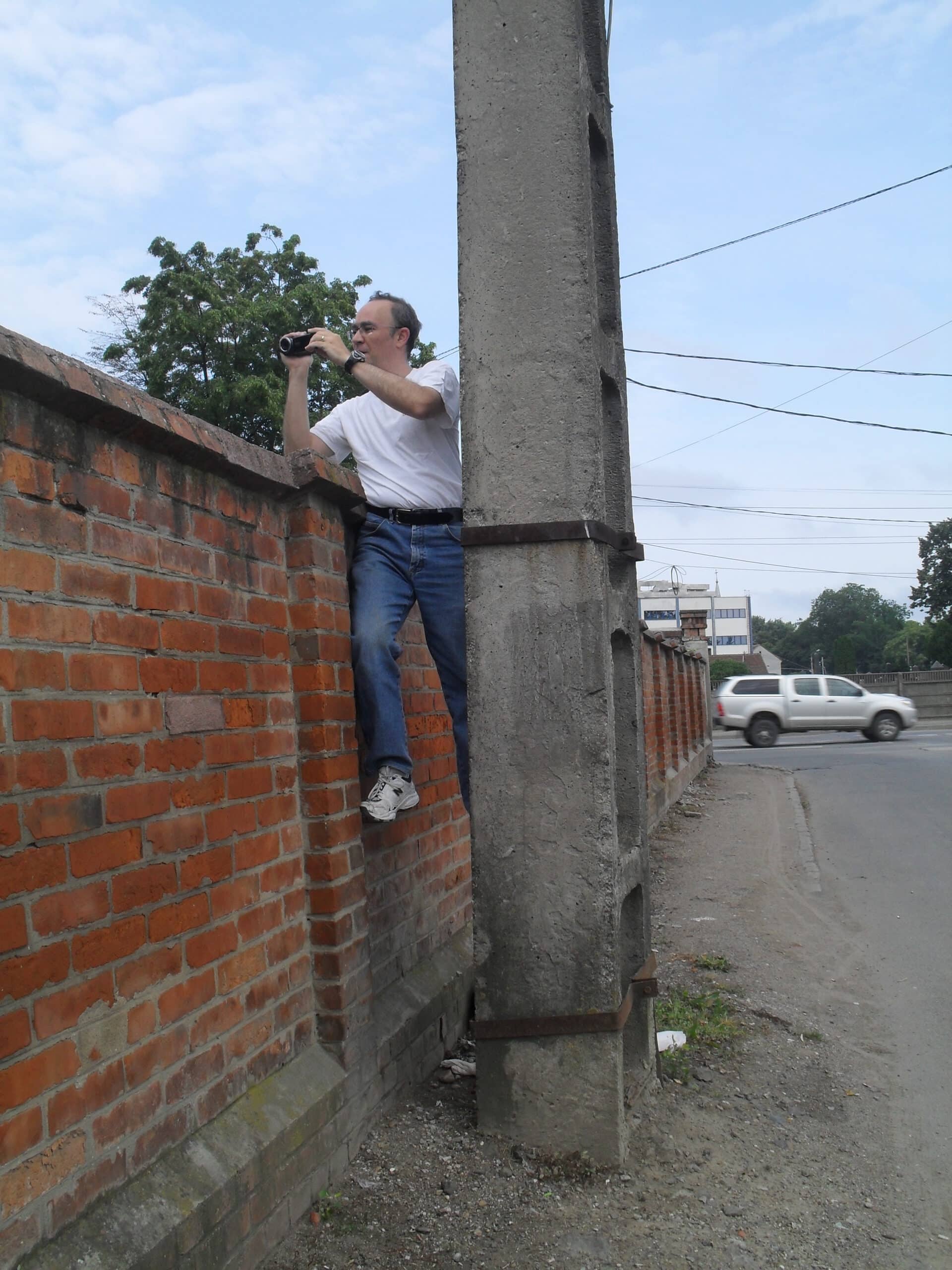 Photo of genealogist Daniel Horowitz taking a photo over a brick wall