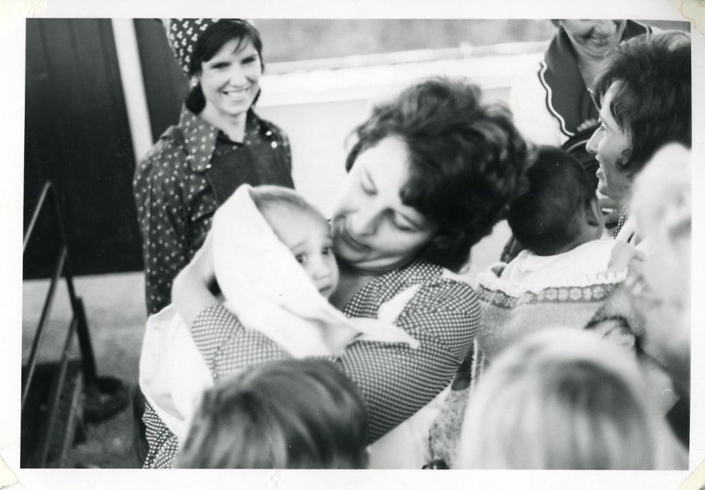 Kims Adoptivmutter Janet Catford hält ihn zum ersten Mal in Adelaide, 26. November 1973. Foto koloriert und verbessert von MyHeritage