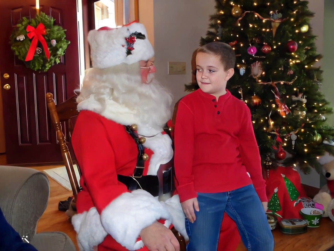 En dreng giver julemanden en grundig evaluering. Foto forbedret og farverne restaureret af MyHeritage