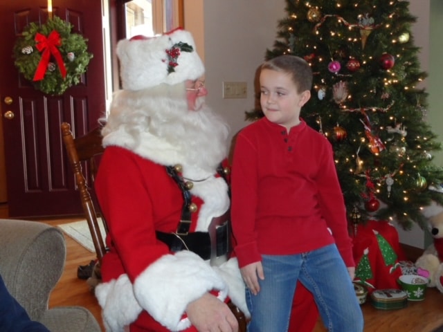Ein Junge schmunzelt auf dem Schoß des Weihnachtsmannes. Foto verbessert und Farben restauriert mit MyHeritage