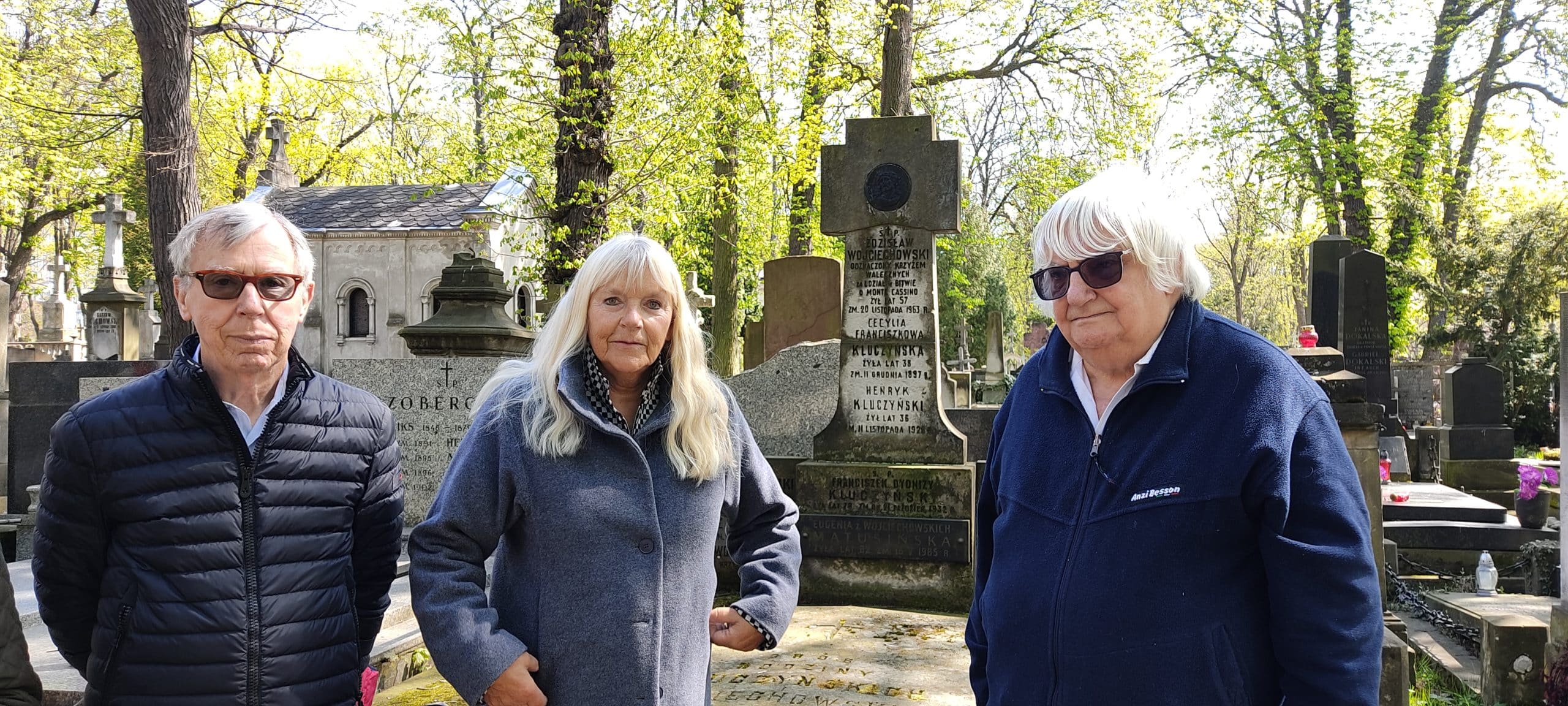 Two women and a man standing by a headstone