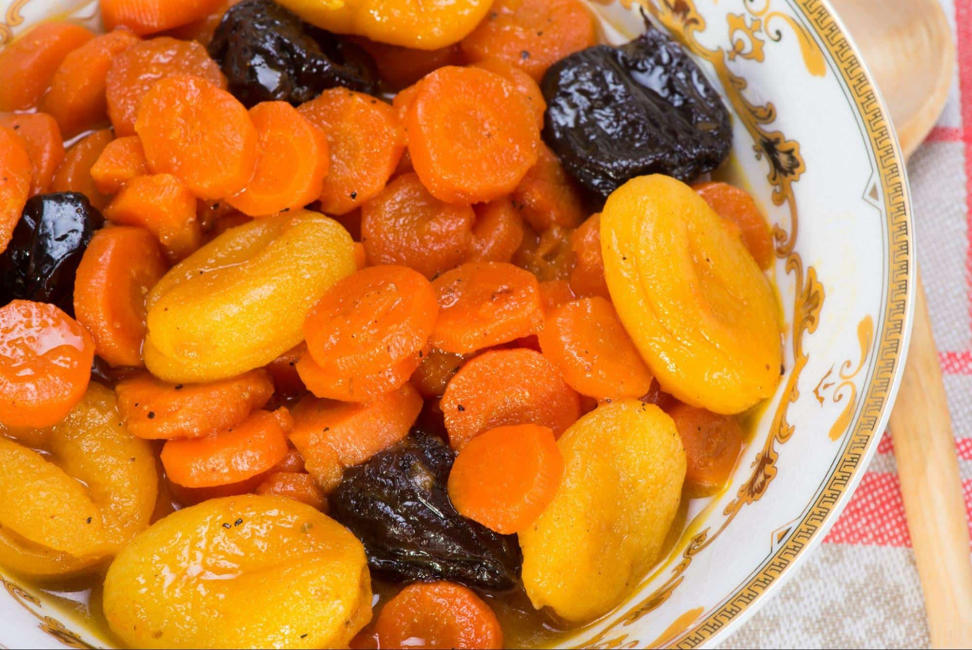 Photo of bowl with tzimmes dish, made with carrots, apricots, and prunes